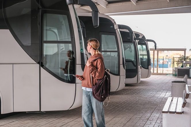 Jeune femme attendant devant un autocar